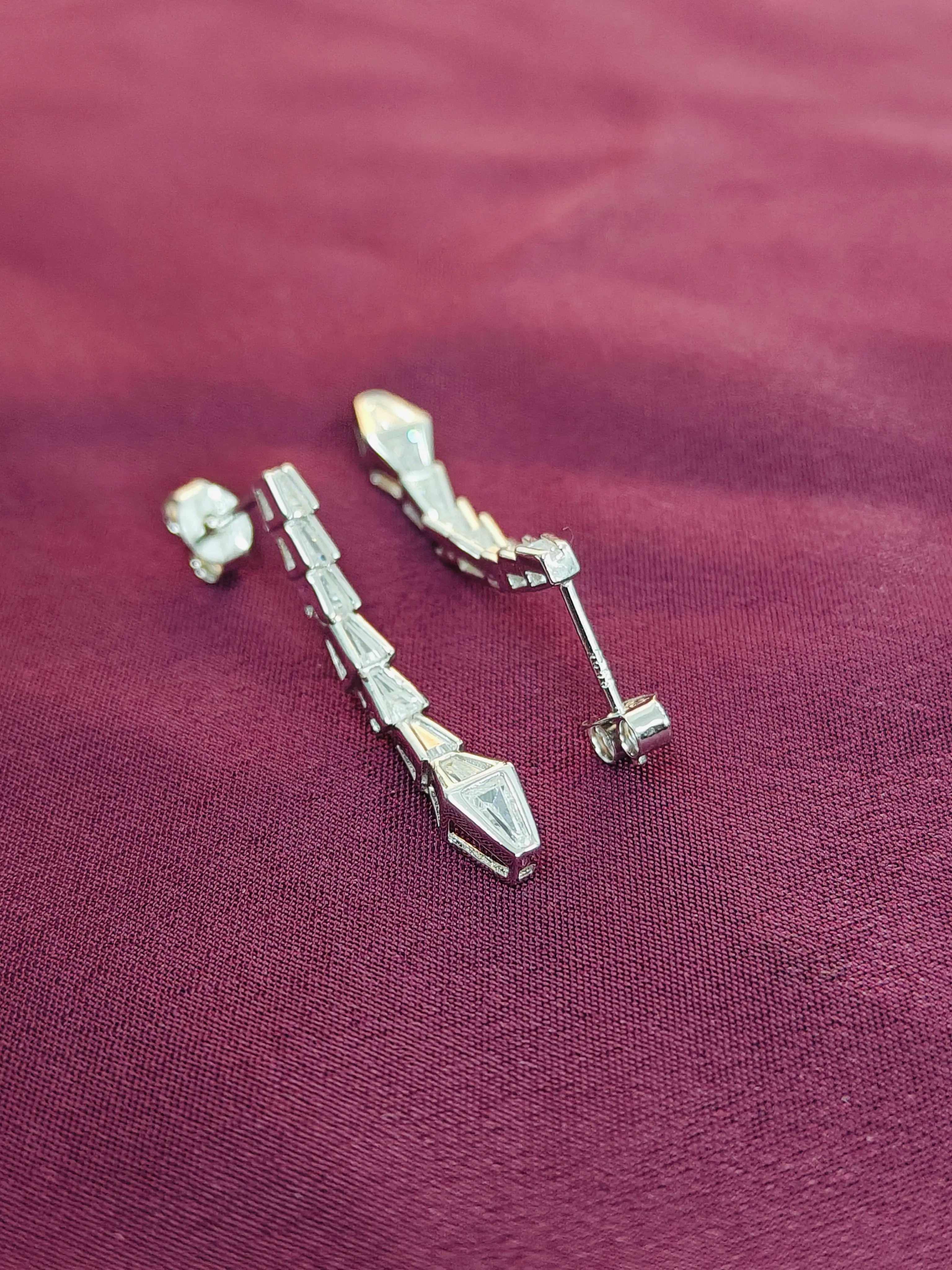 Pair of silver earrings on a purple fabric background